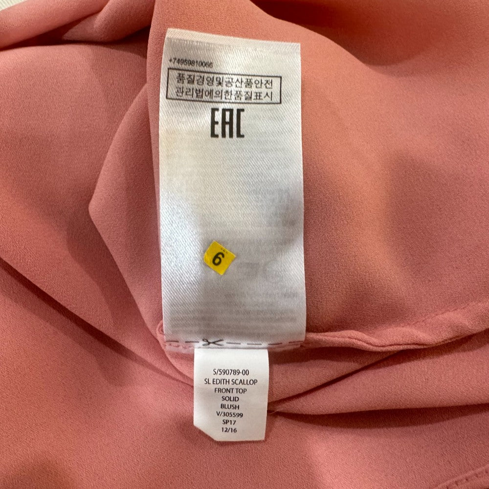 Clothing tag view of Banana Republic top Fabric with a label on a pink background