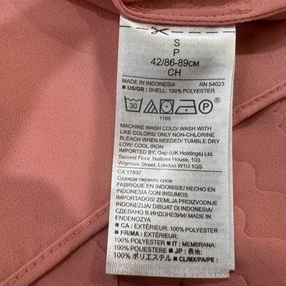 Clothing material label on a Banana Republic peach top with text and symbols.