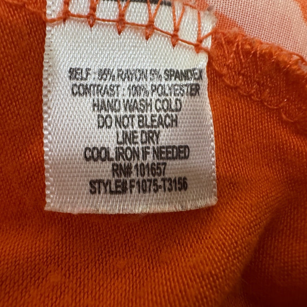 Clothing care tag on Femme by Tresics blouse with care instructions on an orange background