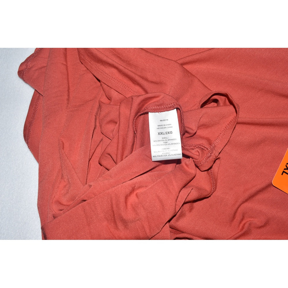 Clothing tag on Joan Vass red shirt on a light gray background