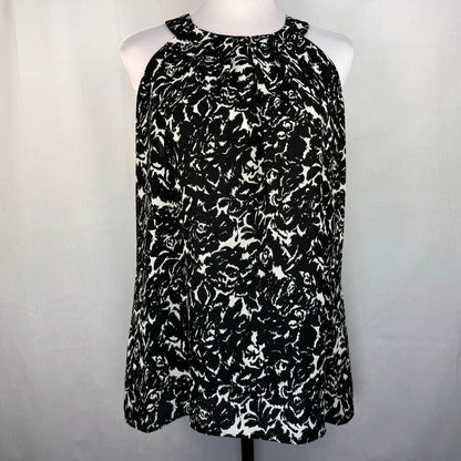 A sleeveless halter-neck top with a black and white abstract floral pattern, displayed on a white mannequin torso against a light gray fabric backdrop.