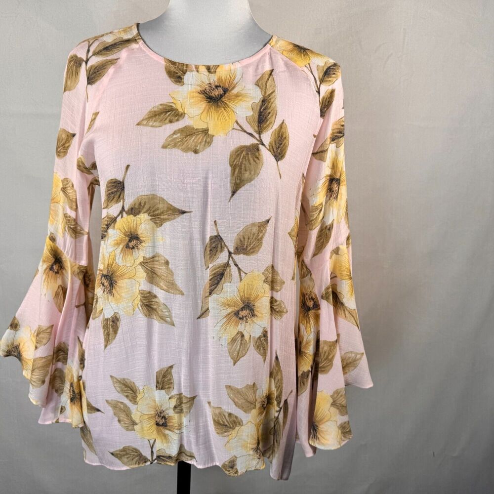 A light pink long-sleeve blouse with a yellow and brown floral print, displayed on a mannequin against a neutral gray background.