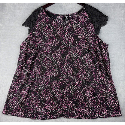 A women's sleeveless top with a black and pink floral print, featuring black lace flutter sleeves, laid flat on a light gray textured background.