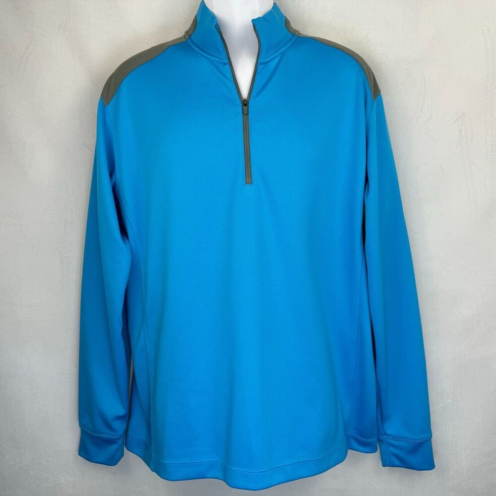 A bright blue long-sleeve quarter-zip pullover jacket with gray shoulder panels, displayed on a white mannequin torso against a light gray textured wall.