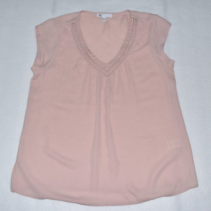 A light pink sleeveless top with a V-neckline and delicate lace trim, laid flat on a light gray background.