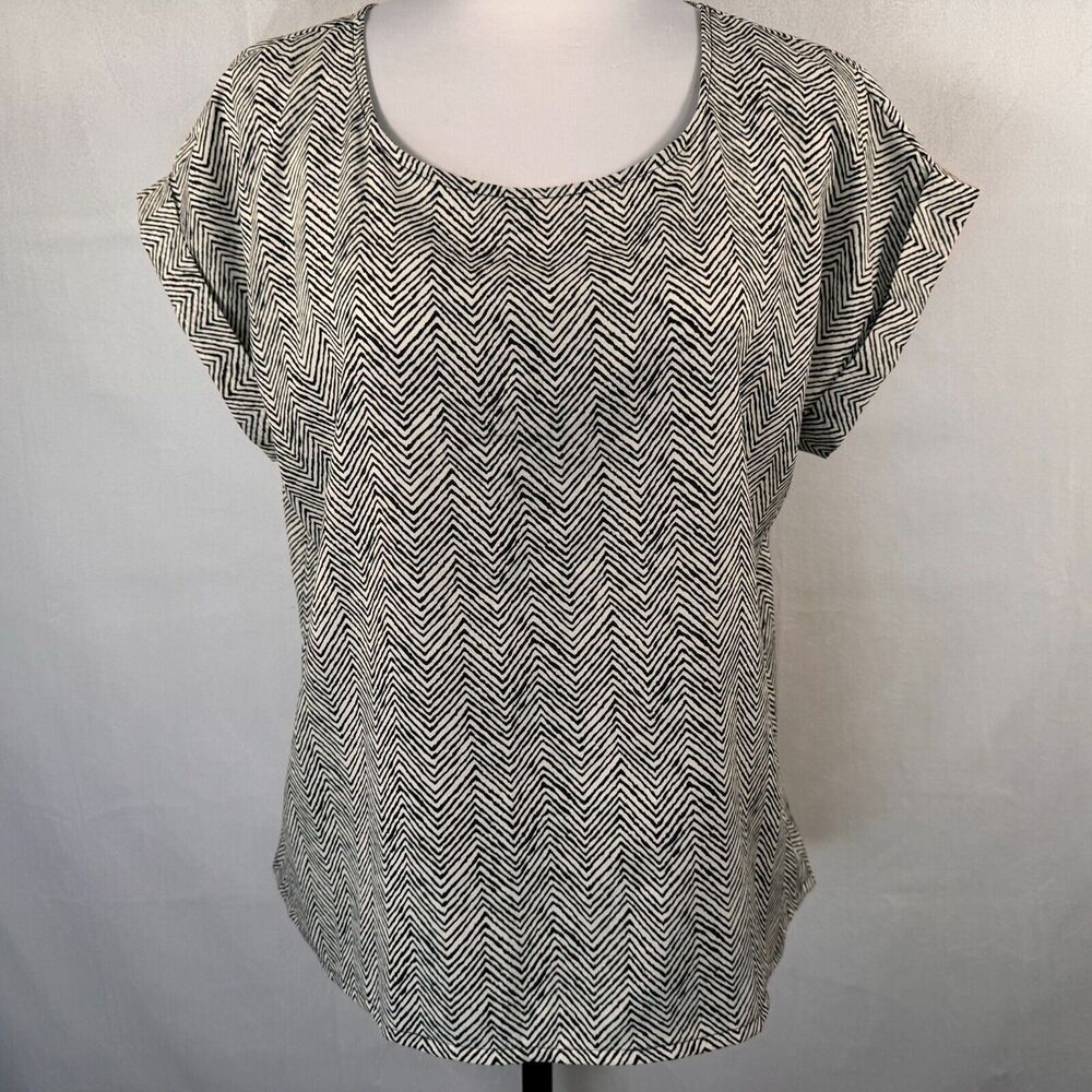 A women's short-sleeve top with a black and white chevron pattern, displayed on a mannequin torso against a light gray fabric backdrop.