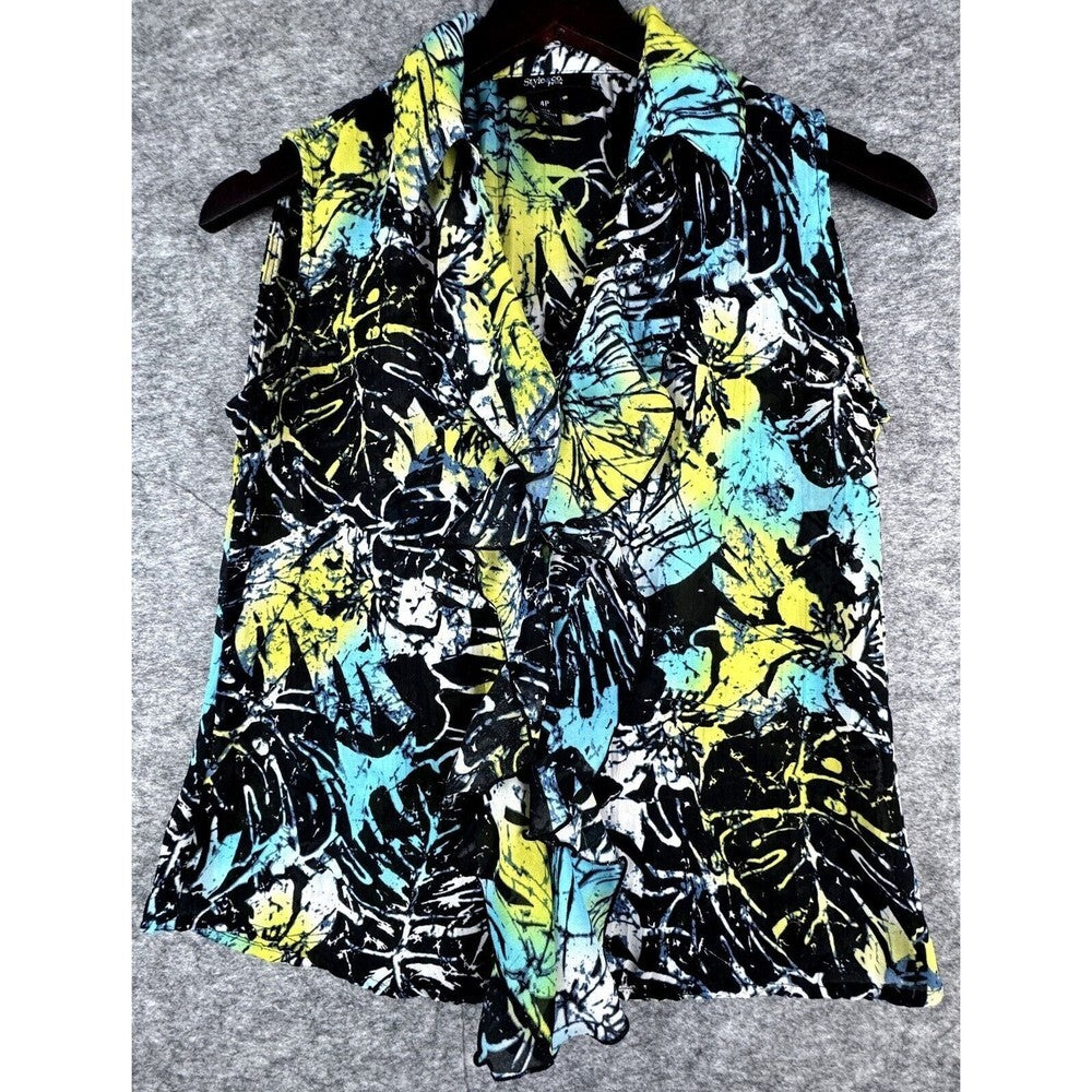 A sleeveless collared shirt with a vibrant tropical leaf print in black, yellow, and turquoise blue, hanging on a dark hanger against a gray textured background.