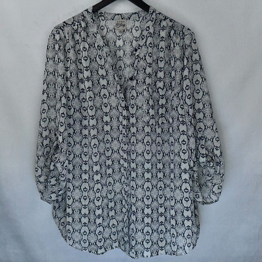 A women's long-sleeve blouse with a black and white snake print pattern, hanging on a black hanger against a light gray fabric backdrop.