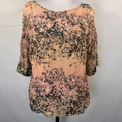 A women's short-sleeve top displayed on a mannequin torso against a light gray background. The top features a mottled, abstract pattern with peach-pink, beige, and black tones.