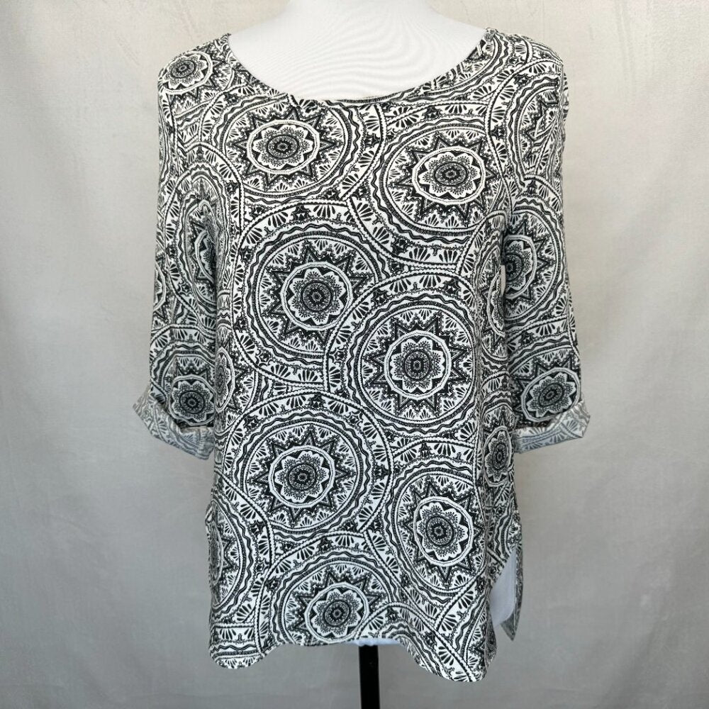 A black and white patterned top with three-quarter sleeves displayed on a white mannequin torso against a light gray fabric backdrop.
