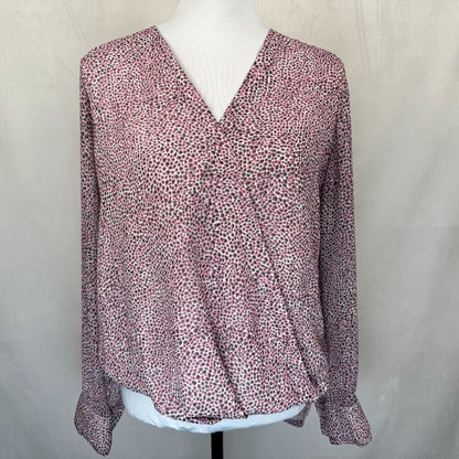 A women's long-sleeve wrap-style blouse with a V-neckline, displayed on a white dress form. The top features an all-over small-scale abstract print in dusty pink, mauve, and dark brown/black tones.