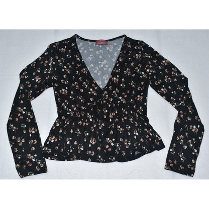 A women's long-sleeve wrap-style blouse with a V-neckline and peplum waist, featuring an all-over small floral print in brown, beige, and white on a black background.