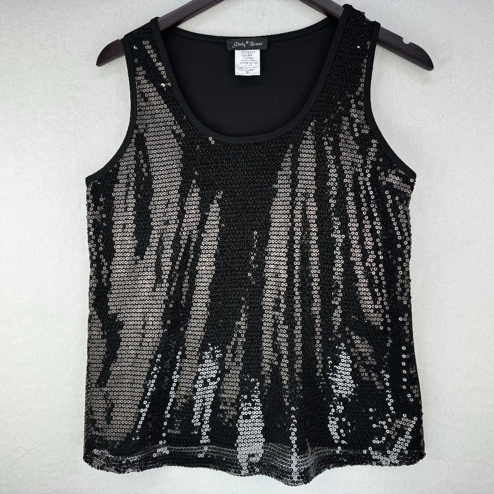A black sleeveless knit top covered in vertical silver sequins, hanging on a dark hanger against a light textured wall.