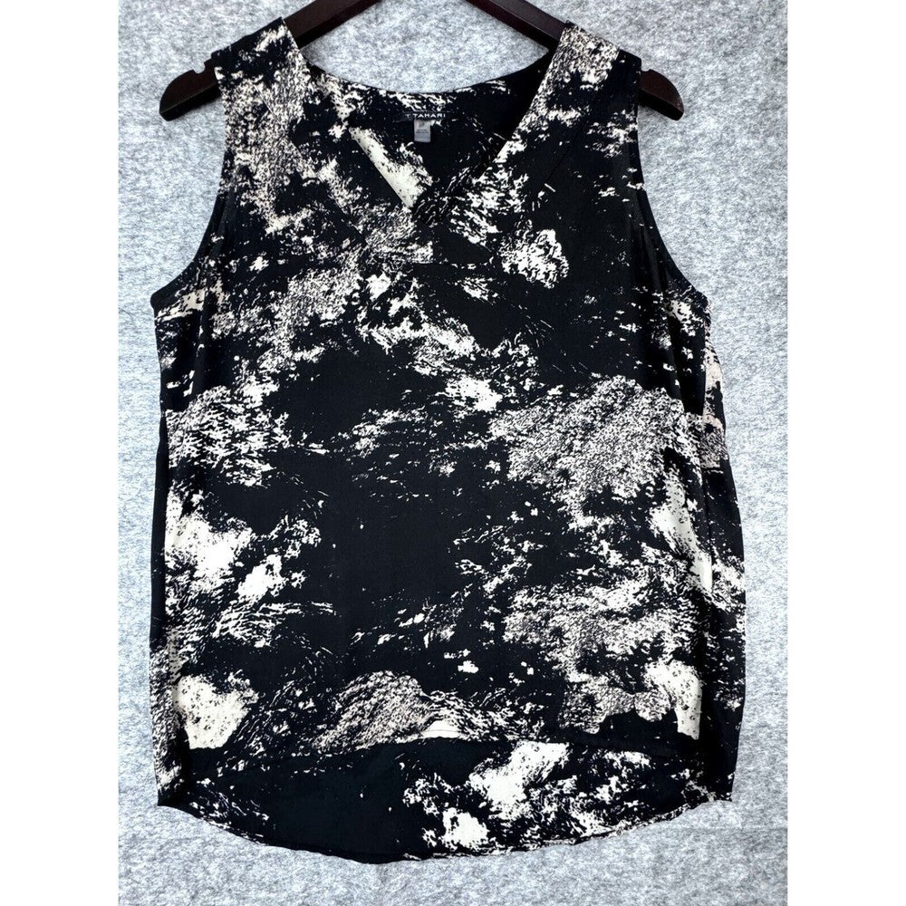 A sleeveless V-neck wrap-style top with a black and white abstract marbled pattern, hanging on a dark wooden hanger against a gray textured background.