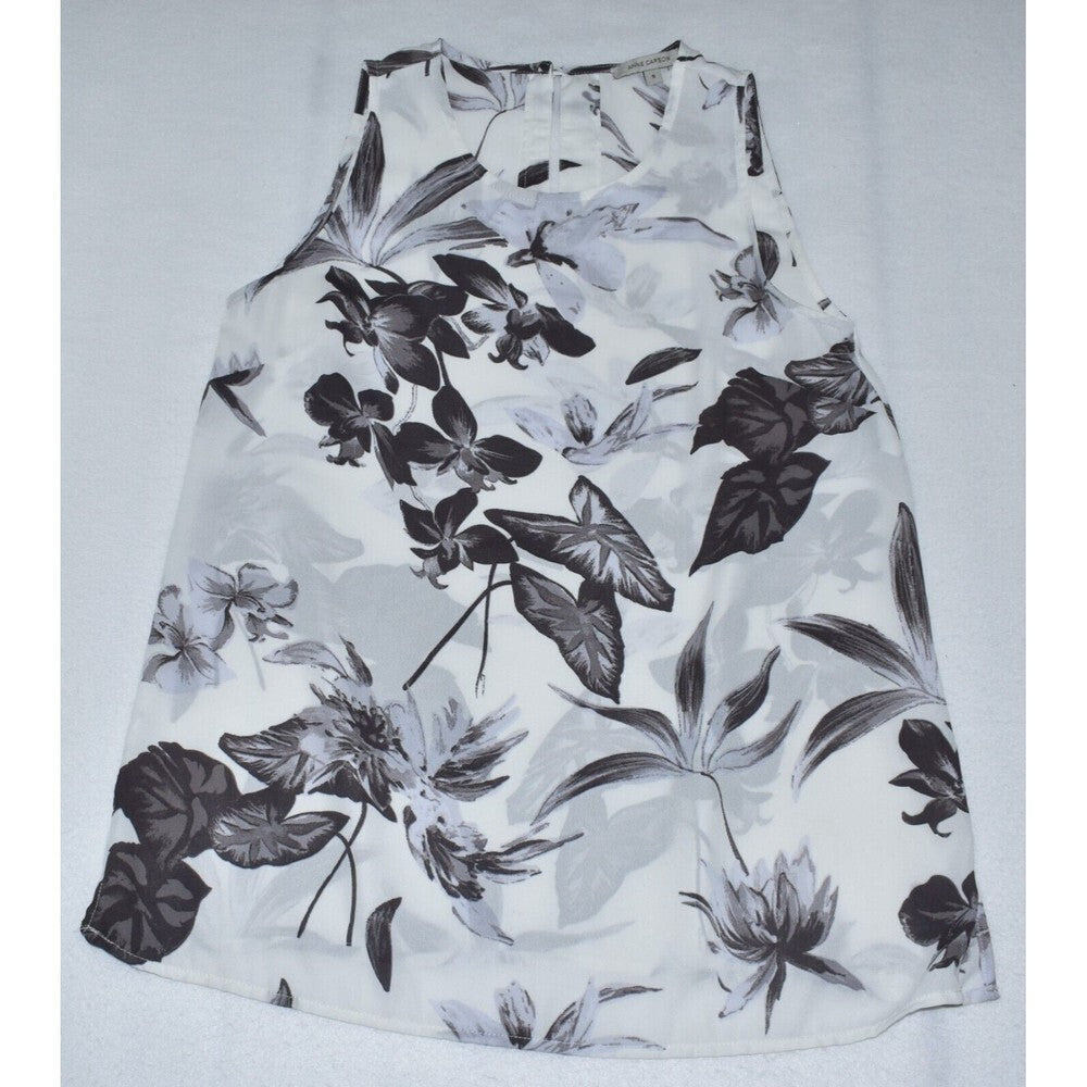 A sleeveless white A-line dress featuring a black and gray botanical leaf and flower print, laid flat against a light gray background.