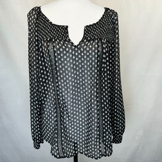 A black long-sleeve blouse with a white geometric pattern, displayed on a white mannequin torso against a white fabric backdrop.