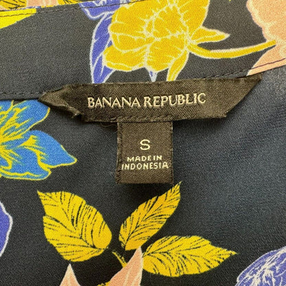 Blusa cruzada Banana Republic, talla S, negra con diseño floral y volantes, manga corta.
