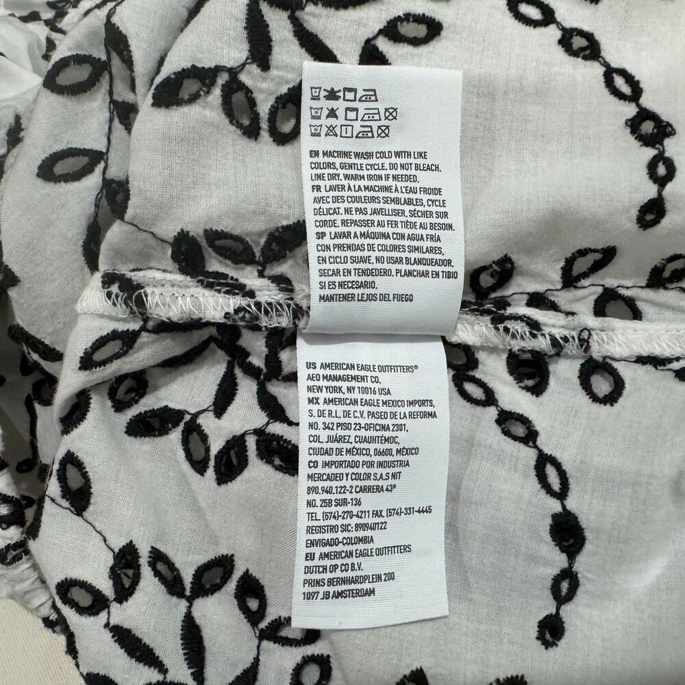 Close-up of a white fabric item with a black abstract pattern and two sewn-in care and manufacturer labels visible.