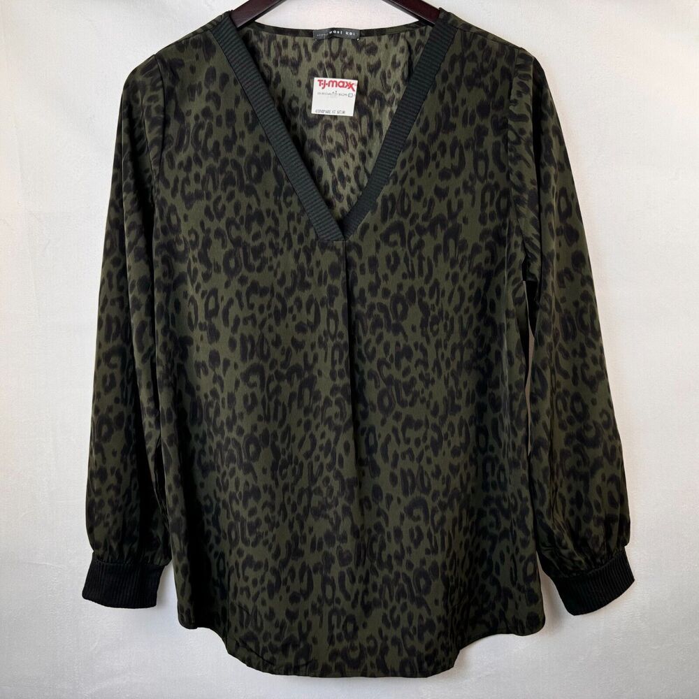 A women's long-sleeve blouse with a dark olive green and black leopard print, featuring a V-neckline with dark ribbed trim and dark cuffs, hanging on a wooden hanger against a white background.