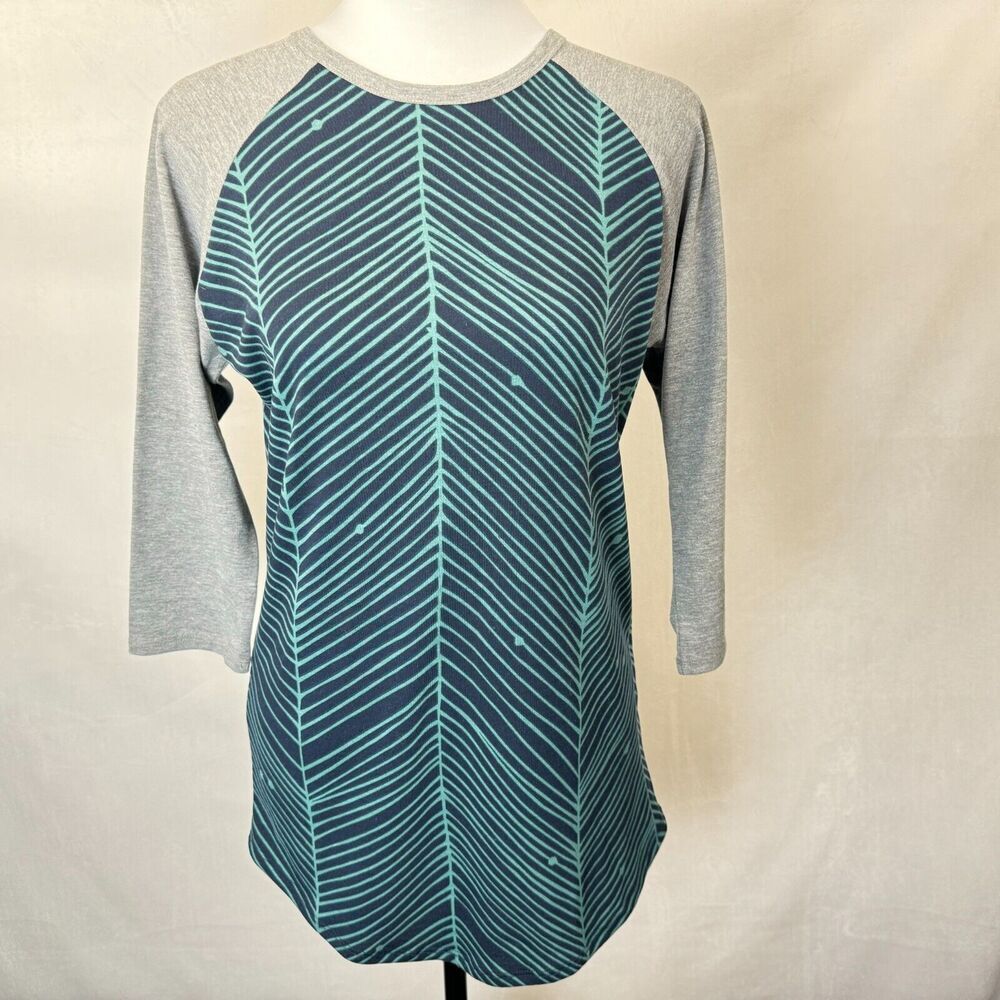 A women's 3/4 sleeve raglan top displayed on a mannequin torso. The shirt features a teal and navy blue chevron pattern on the body and solid heather gray sleeves.