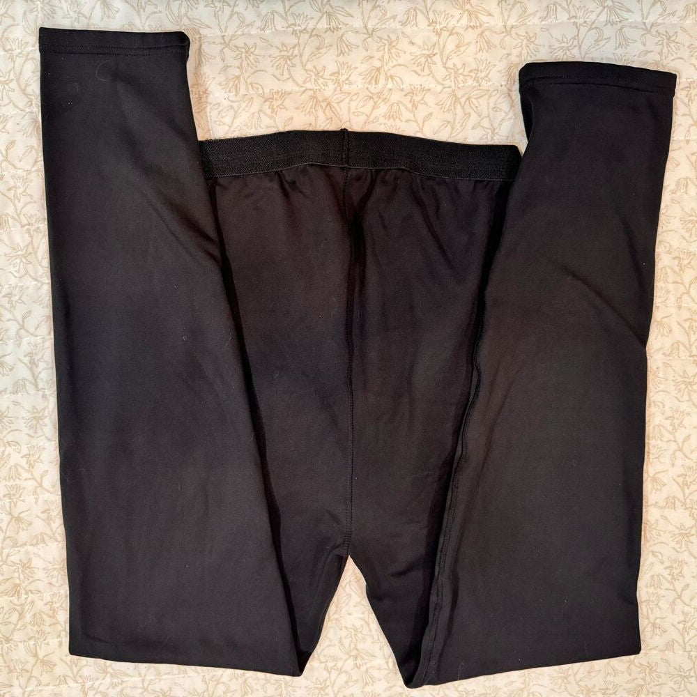 Black pants laid flat on a beige patterned fabric background.