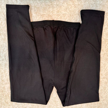 Black pants laid flat on a beige patterned fabric background.
