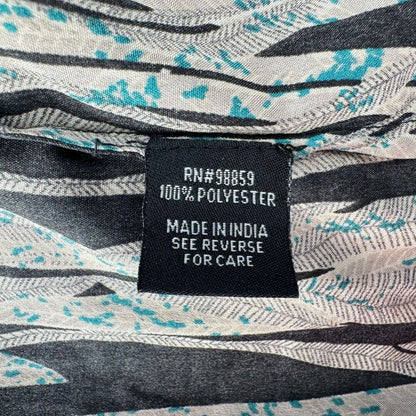 Close-up of a garment's interior neck label reading 'RN#98859 100% POLYESTER MADE IN INDIA SEE REVERSE FOR CARE' on a black patch, with a gray, white, and turquoise abstract patterned fabric visible around it.