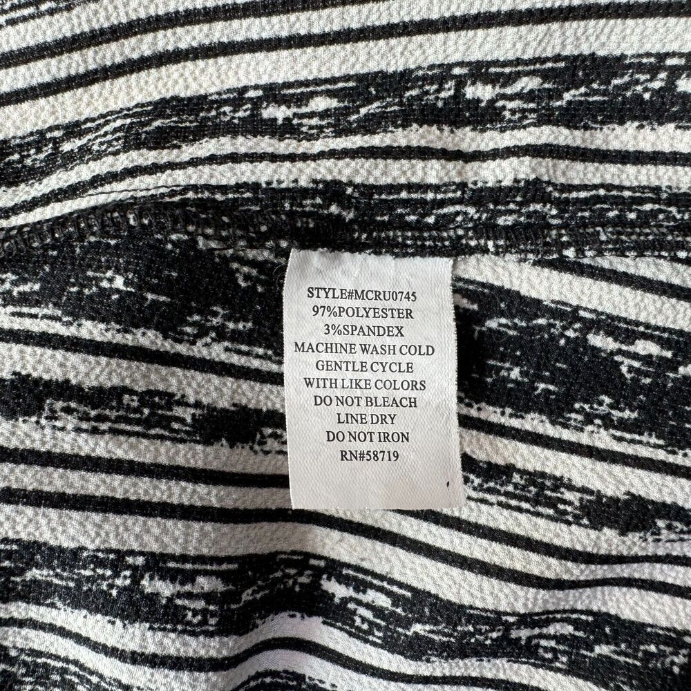 Close-up of a black and white striped fabric garment with a sewn-in white care label showing product details.