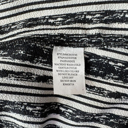 Close-up of a black and white striped fabric garment with a sewn-in white care label showing product details.