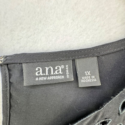 Close-up of a black garment's interior label area showing the 'ana A NEW APPROACH' brand tag and a size '1X MADE IN INDONESIA' tag on a light gray fabric background.