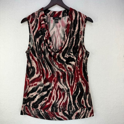 A sleeveless cowl-neck top with an abstract zebra-like pattern in red, black, and beige, hanging on a dark wooden hanger against a textured off-white wall.