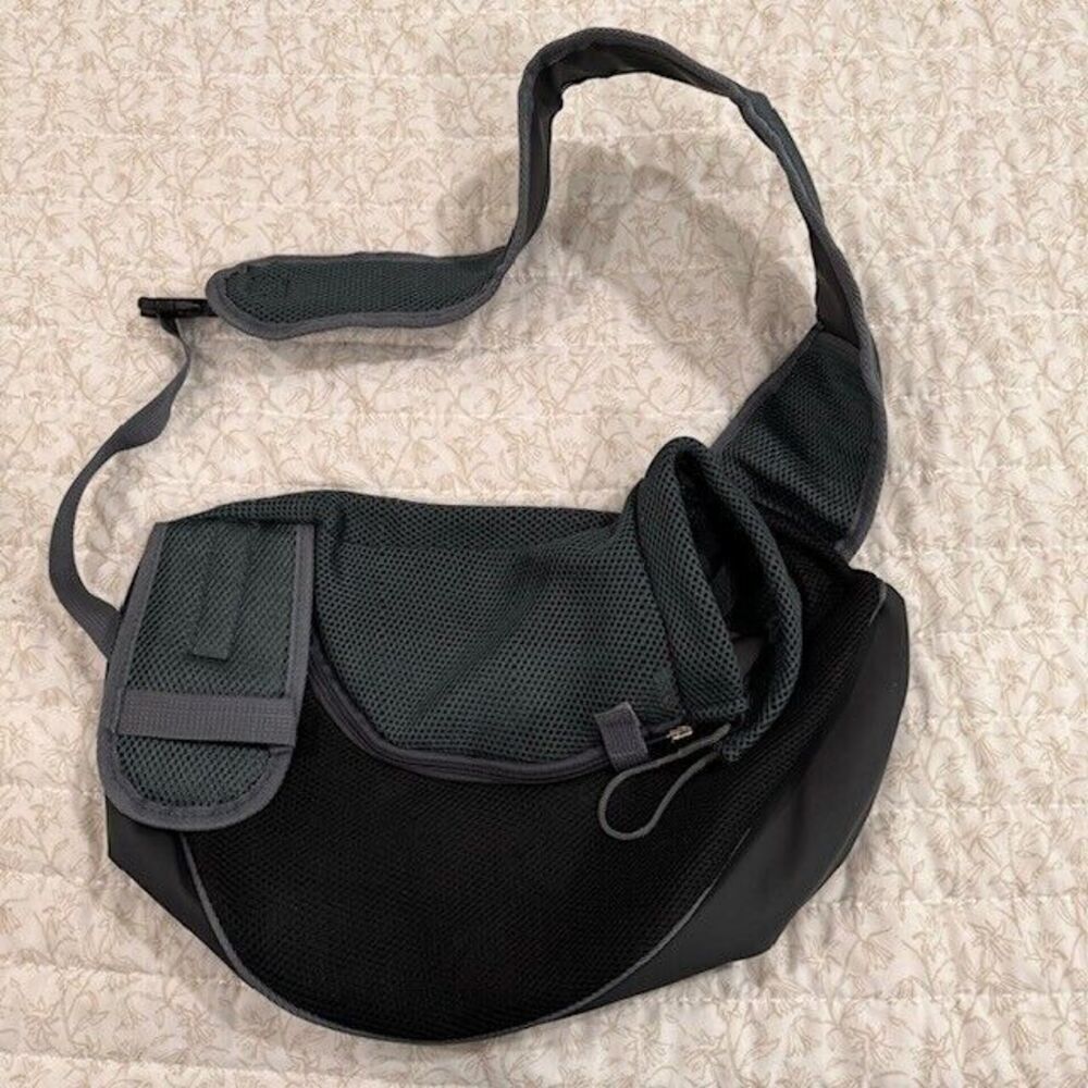 A black mesh and nylon waist bag with a wide adjustable strap, laid flat on a textured beige fabric background.