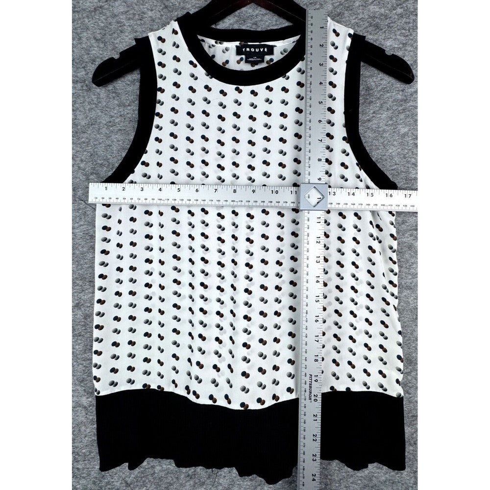 A sleeveless white knit top with a black dotted pattern, black trim, and a black ruffled hem, shown on a hanger with a measuring tape and ruler overlaid to indicate dimensions. The brand label reads 'JANE'S'.