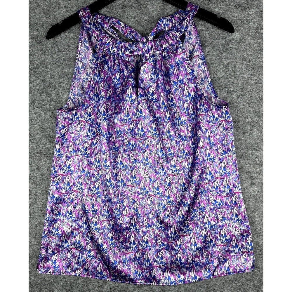 A sleeveless tank top with a purple, blue, and white abstract floral pattern, hanging on a black hanger against a gray textured background.