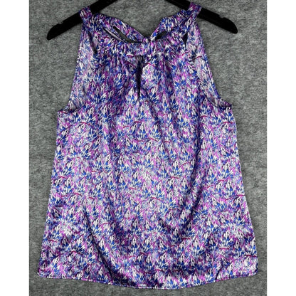 A sleeveless tank top with a purple, blue, and white abstract floral pattern, hanging on a black hanger against a gray textured background.