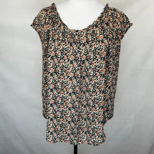 A women's short-sleeve blouse with a dense floral print, displayed on a white mannequin torso against a light gray fabric backdrop.