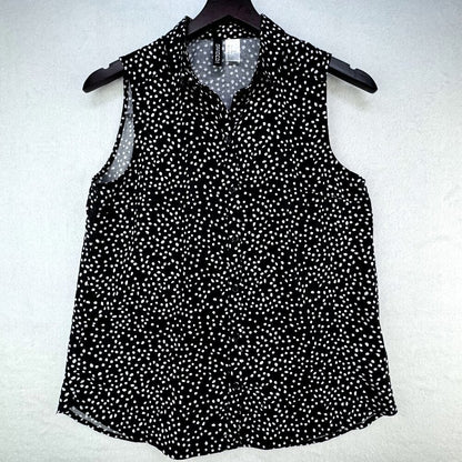 A sleeveless black blouse with a white micro-dot pattern, featuring a pointed collar and button-down front, hanging on a black hanger against a textured white background.