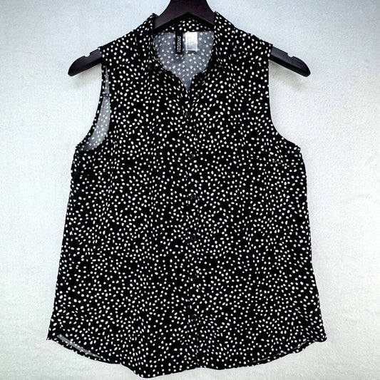 A sleeveless black blouse with a white micro-dot pattern, featuring a pointed collar and button-down front, hanging on a black hanger against a textured white background.