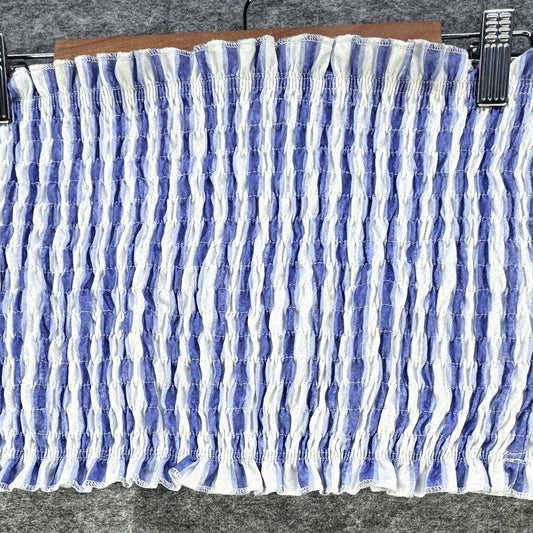 A smocked fabric panel with vertical ruching in blue and white, shown hanging from metal clips on a wooden hanger against a gray textured background.