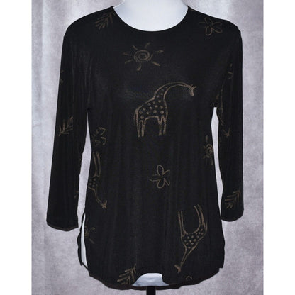 A black long-sleeve tunic top with a textured knit fabric, featuring a whimsical giraffe and sun pattern in a metallic gold or bronze color, displayed on a white mannequin torso against a gray curtain background.