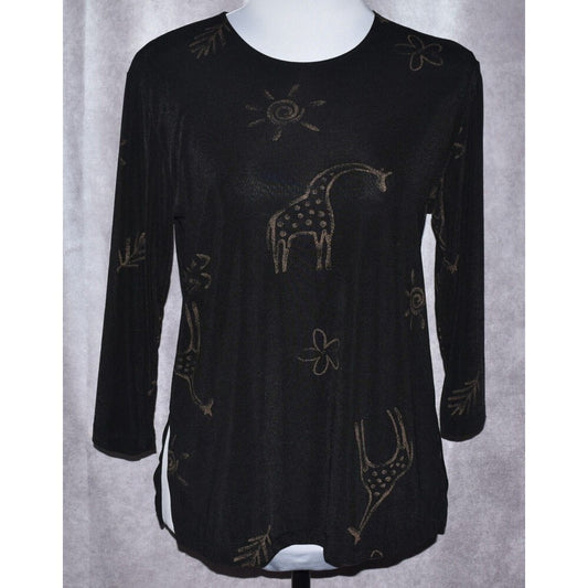 A black long-sleeve tunic top with a textured knit fabric, featuring a whimsical giraffe and sun pattern in a metallic gold or bronze color, displayed on a white mannequin torso against a gray curtain background.
