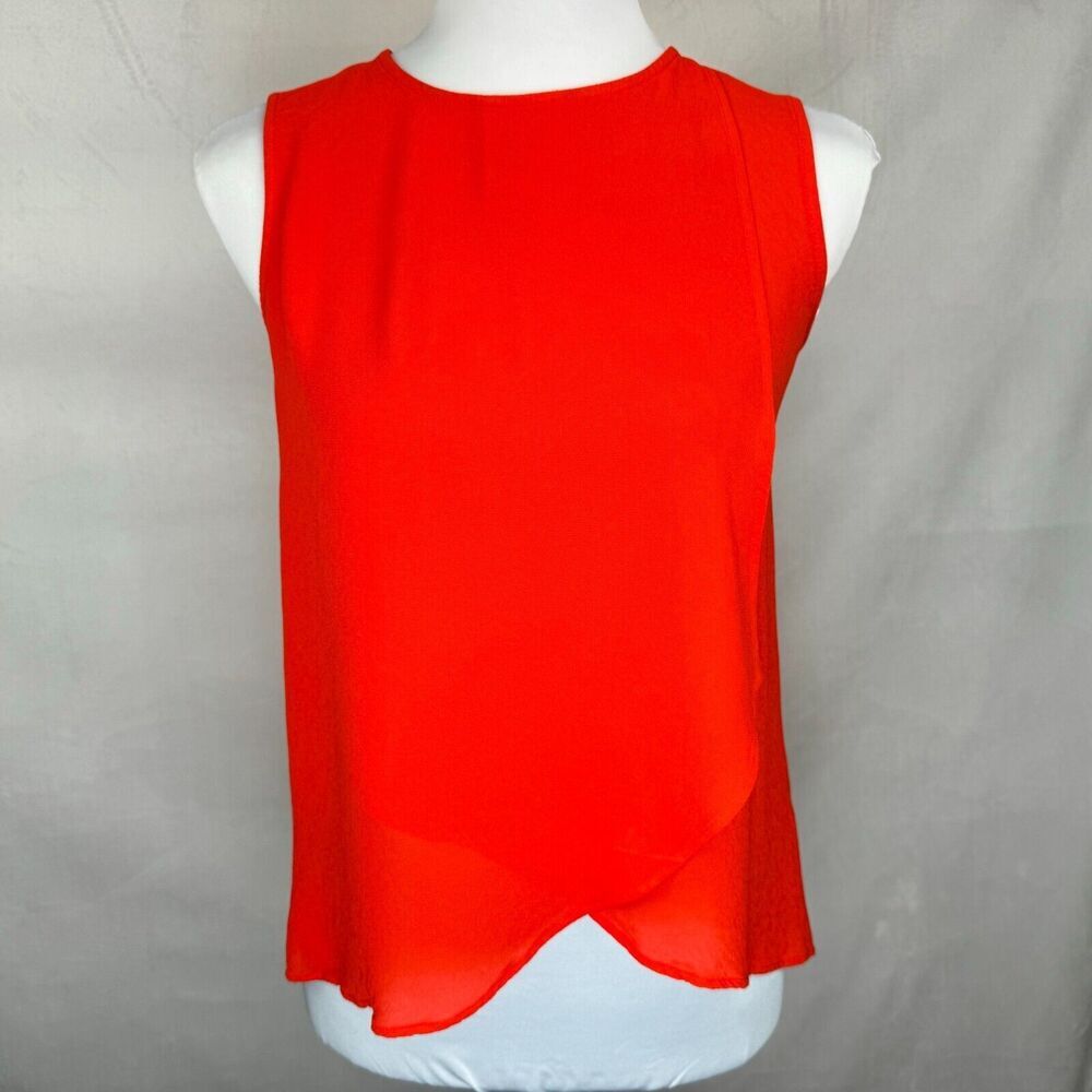 A bright red sleeveless top displayed on a white mannequin torso against a light gray fabric backdrop.