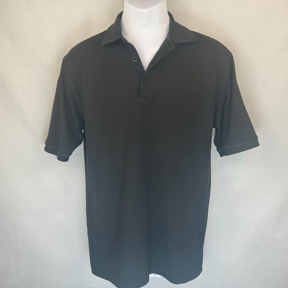 A black short-sleeve polo shirt displayed on a white mannequin torso against a light gray fabric backdrop.
