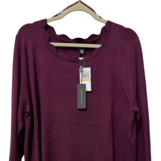 A long-sleeve scoop-neck knit top in deep plum purple, hanging on a beige hanger with retail tags attached against a plain white background.