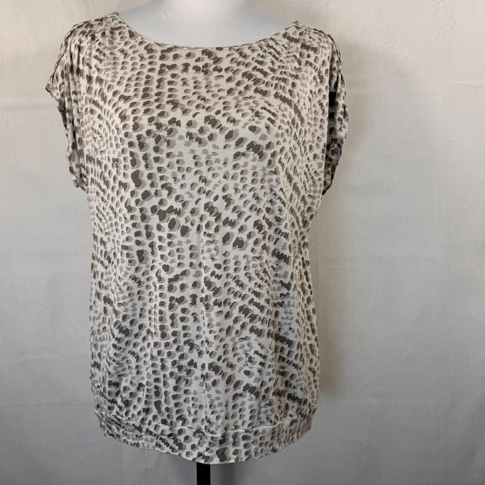 A short-sleeve scoop-neck blouse with an abstract leopard-like spot pattern in beige, brown, and gray, displayed on a mannequin torso against a light gray wall.