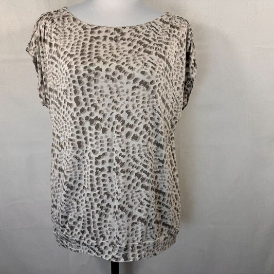 A short-sleeve scoop-neck blouse with an abstract leopard-like spot pattern in beige, brown, and gray, displayed on a mannequin torso against a light gray wall.