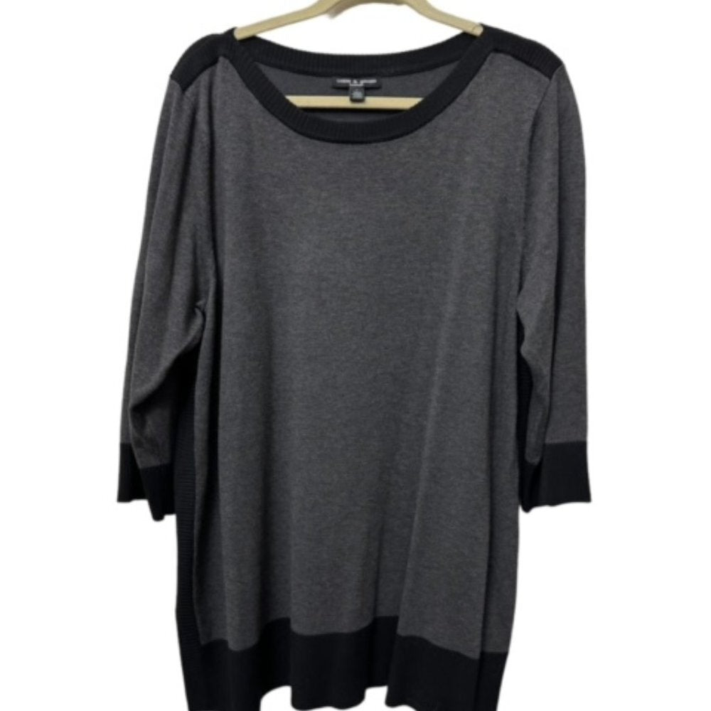 A dark gray knit top with black contrast panels at the shoulders, cuffs, and hem, hanging on a wooden hanger against a white background.