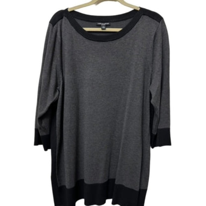 A dark gray knit top with black contrast panels at the shoulders, cuffs, and hem, hanging on a wooden hanger against a white background.