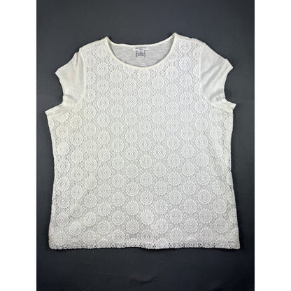 A white short-sleeve top with an all-over circular lace overlay pattern, laid flat on a dark gray background.