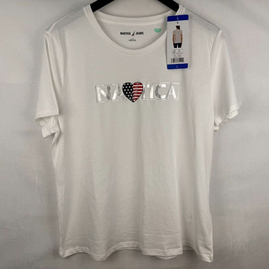 A white short-sleeve crewneck t-shirt by Nautica, featuring a 'N A T I C A' graphic across the chest with a heart in an American flag pattern. The shirt is hanging on a black hanger against a light gray fabric backdrop, with its retail hangtag still attached.